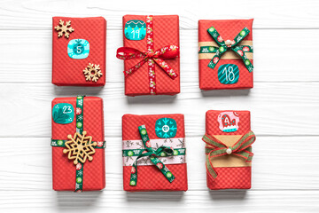 Obraz premium Handmade wrapped red, green gift boxes decorated with ribbons, snowflakes and numbers, Christmas decorations and decor on white table Xmas advent calendar concept Top view Flat lay Holiday card