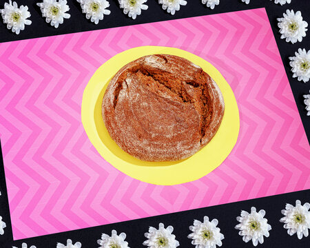 View from above rustic round bread loaf on pink zigzag background
