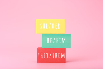 Correct pronouns for different genders hand written on multicolored rectangles against bright pink...