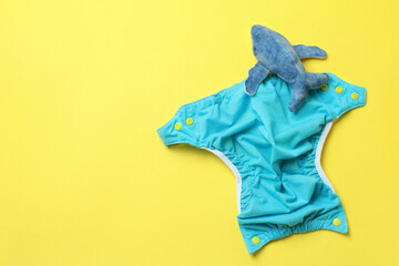 Concept of baby clothes with reusable diapers on yellow background