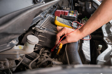 Auto mechanic measures voltage with multimeter.