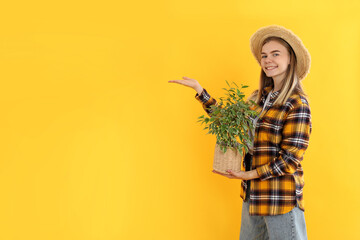 Young attractive girl gardener on yellow background