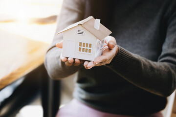 Female hand holding a house model, insurance concept and home loan.