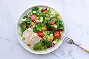 Caesar salad with chicken, lettuce, tomato, cheese and sauce on white background