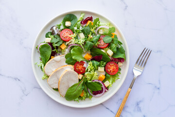 Caesar salad with chicken, lettuce, tomato, cheese and sauce on white background