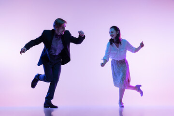 Dynamic portrait of young dancers, man and woman in vintage style outfits dancing swing isolated on...