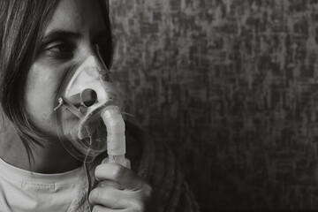 young woman is breathing in a nebulizer inhaler mask. Black and white