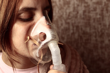 young woman is breathing in a nebulizer inhaler mask - obrazy, fototapety, plakaty