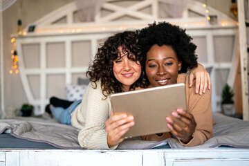 Beautiful happy gay couple having fun and good time together with tablet at home