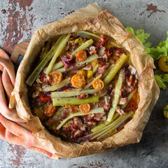 baking sheet with baked celery with bacon and cherry tomatoes on the table
