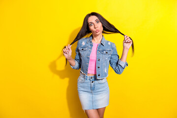 Portrait of attractive girlish cheerful girl having fun grimacing making tails isolated over bright yellow color background