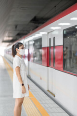 woman wearing Protective face mask prevention coronavirus inflection during waiting train. public...
