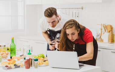 Couple with wine browsing laptop at table