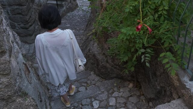 Back view of woman walking down stairs in Monsanto historic center, Portugal. Handheld
