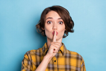 Photo of speechless girl finger cover lips ask keep silence wear checkered plaid shirt isolated blue color background