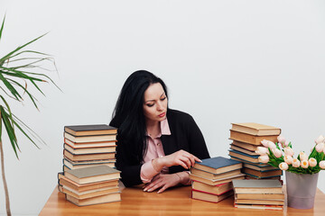 beautiful brunette woman in a business suit learns to read books at the table