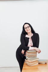 beautiful brunette woman in a business suit teacher with books at the table
