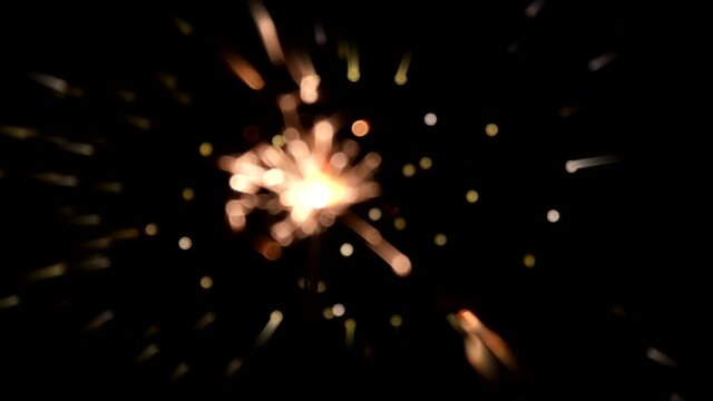 Burning sparkler on the background of glowing garlands out of focus.