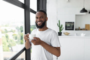 Smiling African American man drinking coffee near window