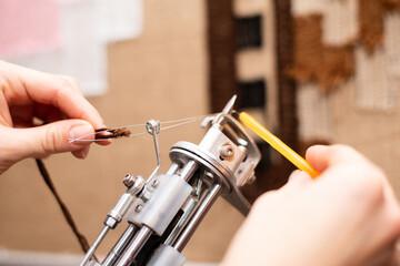 Tufting process - making a tufted rug using a tufting gun and acrylic yarn. The process of refueling the tufting gun with the needle threader.