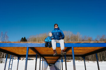 Little boy with father on pier in winter.