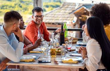 Group of friends at reunion eating and drinking wine.