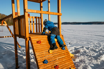 Naklejka na ściany i meble Boy on the playground in winter day.