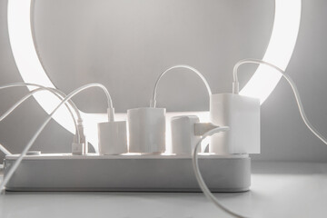 Many chargers plugged into maltiple electrical outlet on white background. Concept of electricity...
