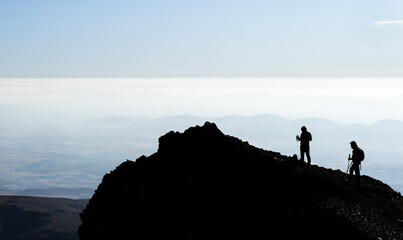 Silhouette of hikers on mountain top on clear sky background
