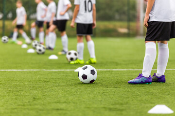 Soccer Players Standing in Line With Soccer Balls on Traininf Unit. Football School For Kids. Young Boys Practicing Soccer on Grass Pitch. Children in White and Black Soccer Kit