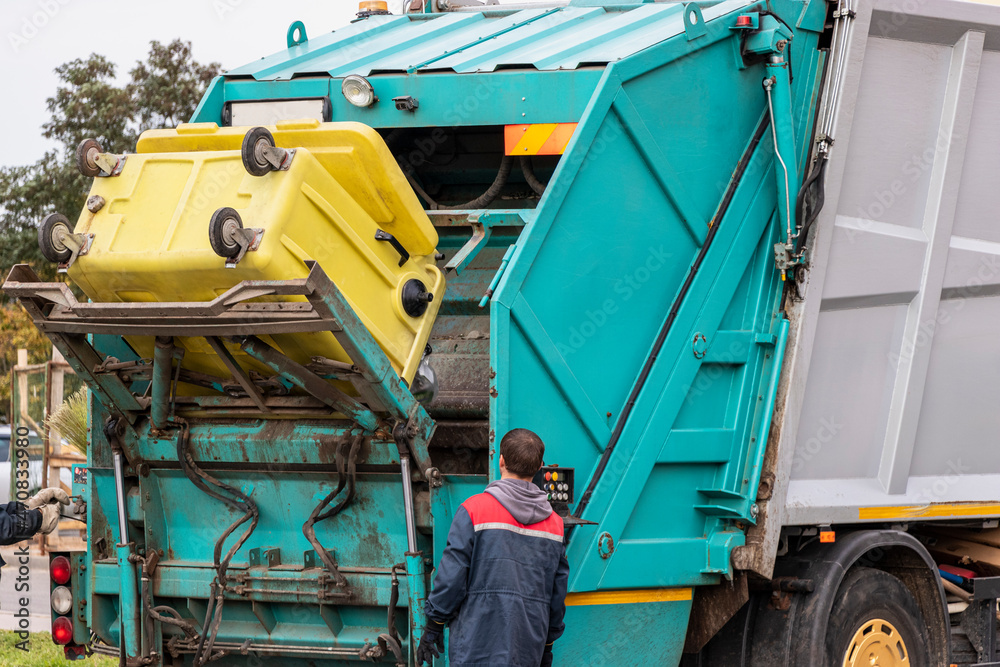 Poster A garbage truck picks up garbage in a residential area. Workers load a container with garbage. Separate collection and disposal of garbage.