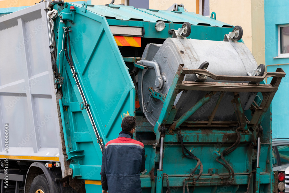 Poster A garbage truck picks up garbage in a residential area. Workers load a container with garbage. Separate collection and disposal of garbage.