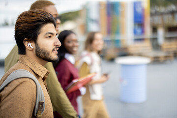 Side view of multiracial students walking on territory of university campus. Concept of education and learning. Idea of student lifestyle