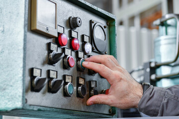 The machine operator of a metalworking machine switches switches and buttons on the equipment...