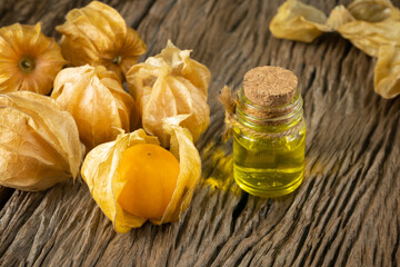 Cape Gooseberry and extract oil (Physalis  Peruviana) or Ground cherries, Physalis minima, Pygmy ground cherry, Inca berry, Golden strawberry, Strawberry tomato, Husk tomato on wooden table.