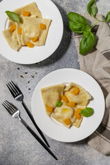Homemade Italian pumpkin ricotta ravioli on a gray stone tabletop. Top view flat lay background.