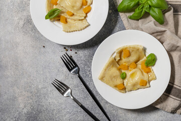 Homemade Italian pumpkin ricotta ravioli on a gray stone tabletop. Top view flat lay background.