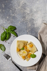 Homemade Italian pumpkin ricotta ravioli on a gray stone tabletop. Top view flat lay background. Copy space.