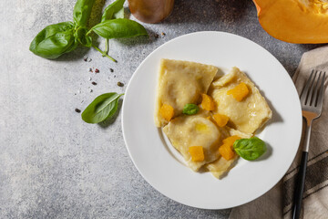 Homemade Italian pumpkin ricotta ravioli on a gray stone tabletop. Top view flat lay background. Copy space.