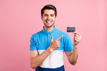 Photo of optimistic brunet young guy point card wear blue t-shirt isolated on pink color background
