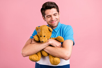 Photo of funny brunet young guy hug toy wear striped polo isolated on pink color background