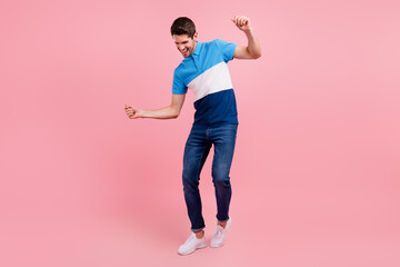 Fototapeta na wymiar Full length photo of funky brunet young guy dance wear polo jeans sneakers isolated on pink background