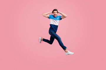 Fototapeta na wymiar Full size photo of impressed brunet young guy run wear polo jeans sneakers isolated on pink background