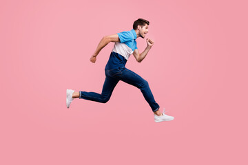 Fototapeta na wymiar Full size photo of lovely brunet young guy run wear polo jeans sneakers isolated on pink background