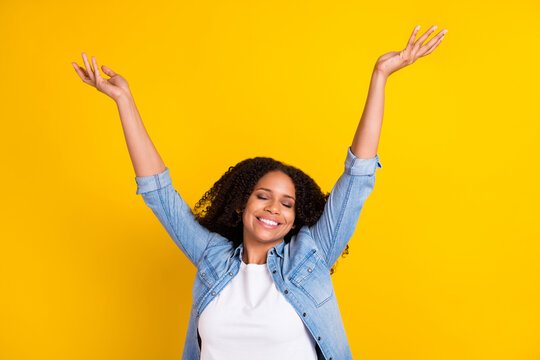 Photo of young happy joyful afro american relaxed woman raise hands enjoy weekend isolated on yellow color background