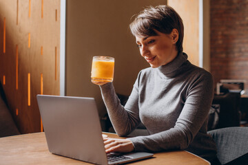 Young woman working on computer and drinking hot tea