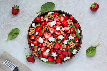 Fresh spinach strawberry salad with feta cheese. Flatlay table top view.