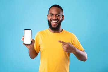 Excited African American man presenting smartphone with blank screen, offering space for website or...