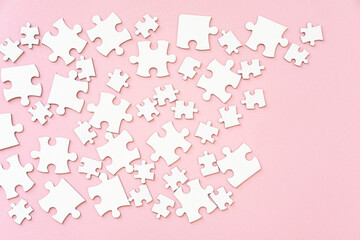 White jigsaw puzzle pieces on pink, top view