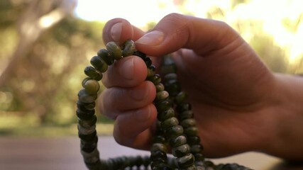Woman is praying, speaking, chanting mantra with a japa mala. Concept for religious practice in Hinduism, Jainism, Buddhism, Sikhism, Islam, and Christianity. 